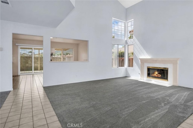 unfurnished living room featuring visible vents, carpet floors, high vaulted ceiling, a fireplace with flush hearth, and tile patterned flooring