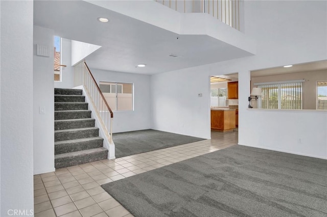 interior space with tile patterned flooring, a high ceiling, recessed lighting, and carpet