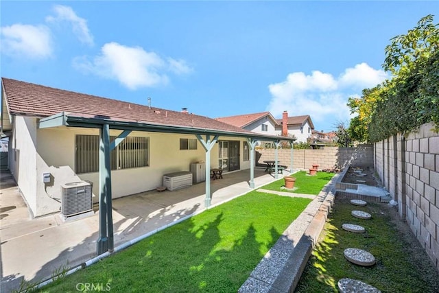 rear view of house with stucco siding, cooling unit, a yard, a fenced backyard, and a patio