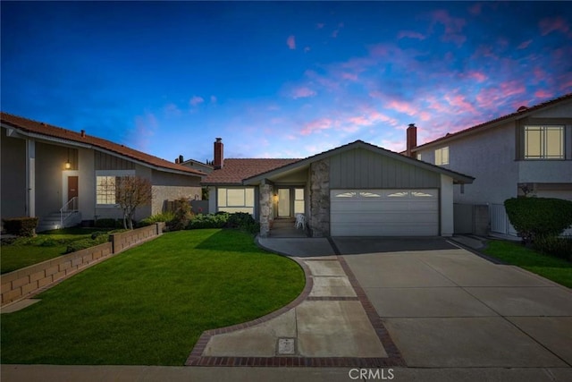 view of front of home featuring an attached garage, a lawn, driveway, and a chimney