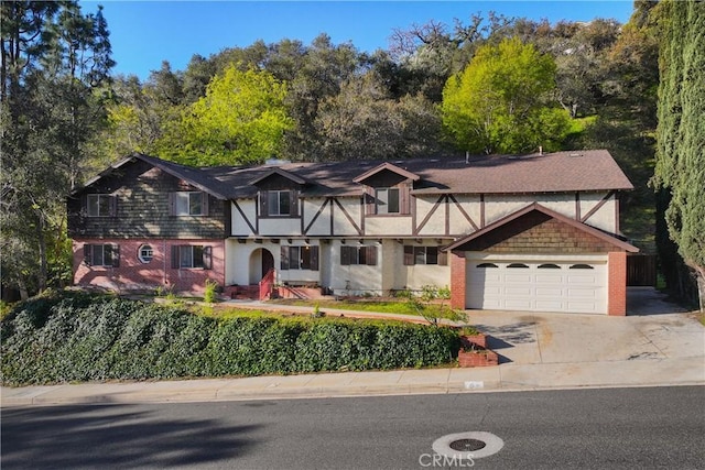 tudor house featuring brick siding, driveway, and an attached garage