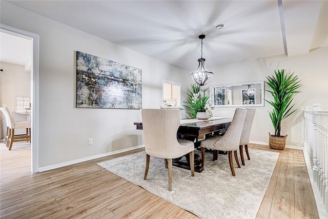 dining area featuring a notable chandelier, light wood-type flooring, and baseboards