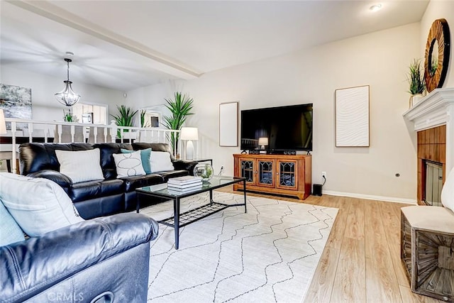 living area featuring beam ceiling, baseboards, and light wood finished floors