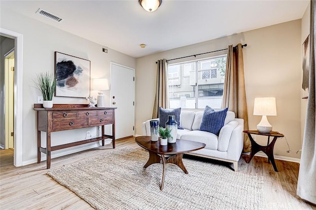 living room with visible vents, baseboards, and light wood-style flooring