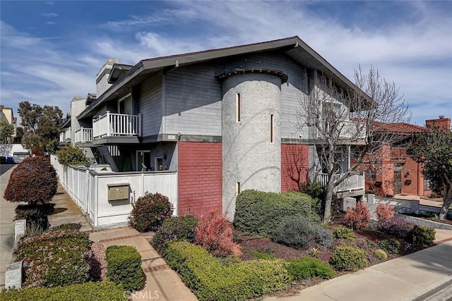 view of side of home featuring a balcony and brick siding