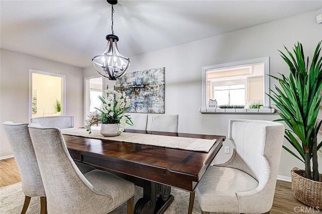 dining room with a chandelier, baseboards, and wood finished floors