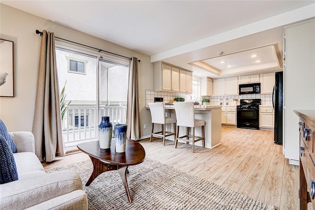 living room with visible vents, baseboards, recessed lighting, light wood-style floors, and a raised ceiling