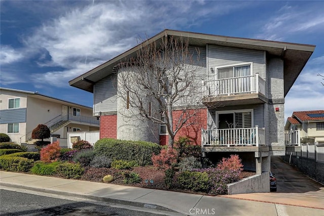 view of front of house with brick siding and a balcony