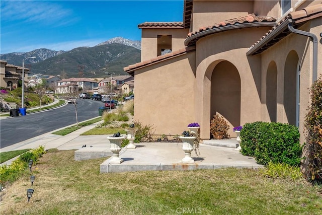 exterior space featuring a tile roof, a mountain view, and stucco siding