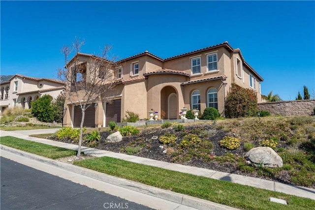 mediterranean / spanish-style home featuring stucco siding, concrete driveway, and a tiled roof