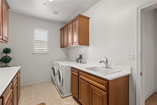 washroom with visible vents, a sink, cabinet space, baseboards, and washing machine and clothes dryer