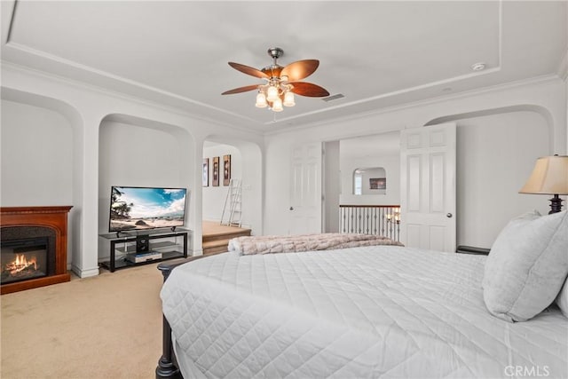 bedroom with visible vents, ornamental molding, light carpet, arched walkways, and a glass covered fireplace