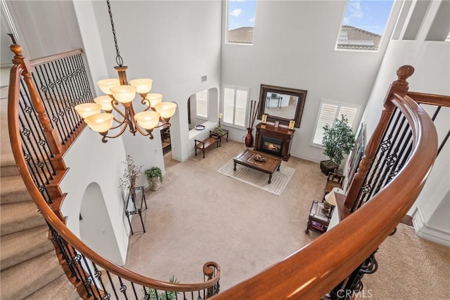 interior space with a wealth of natural light, a high ceiling, an inviting chandelier, and carpet flooring