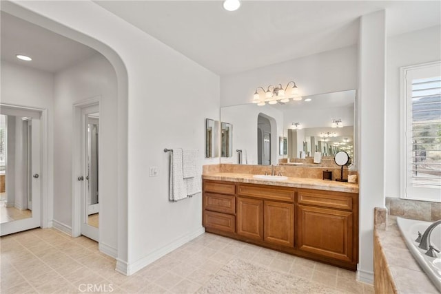 bathroom with a bath, recessed lighting, vanity, and baseboards