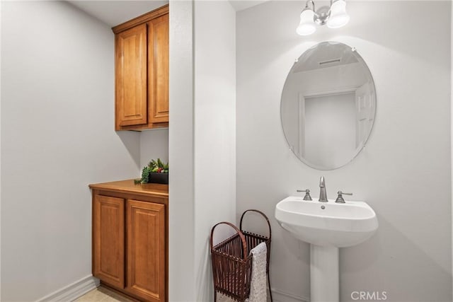 bathroom with a sink, baseboards, and a notable chandelier