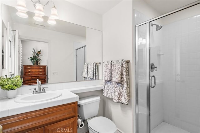 bathroom with vanity, a shower stall, toilet, and visible vents