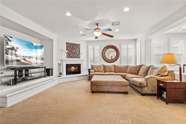 living area with recessed lighting, visible vents, light colored carpet, and a glass covered fireplace