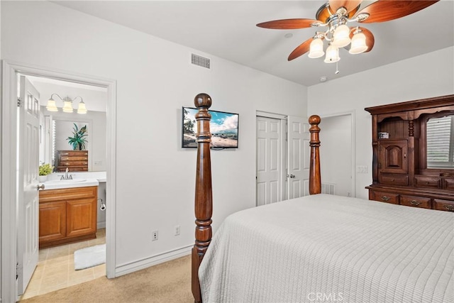 bedroom with a ceiling fan, visible vents, ensuite bath, a sink, and light colored carpet