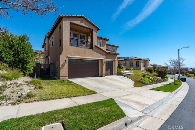 mediterranean / spanish-style house featuring a tiled roof, stucco siding, driveway, a balcony, and an attached garage