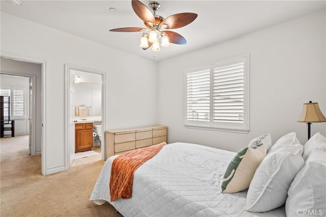 bedroom with baseboards, light colored carpet, ceiling fan, and ensuite bathroom