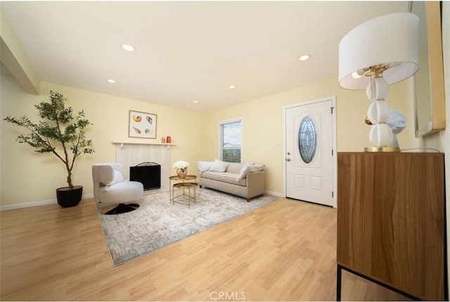 living area featuring a fireplace, recessed lighting, wood finished floors, and baseboards