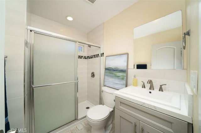 bathroom featuring a shower stall, toilet, and vanity