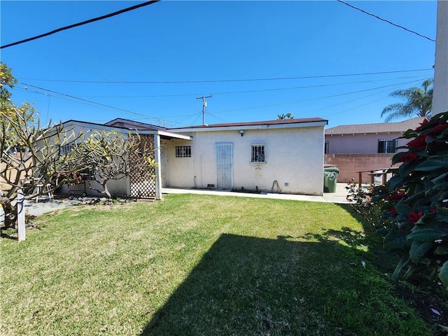 back of house featuring a patio, a lawn, fence, and stucco siding