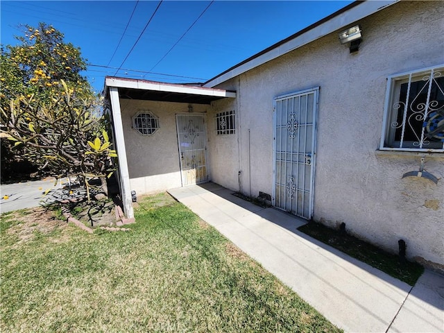 property entrance with a yard and stucco siding