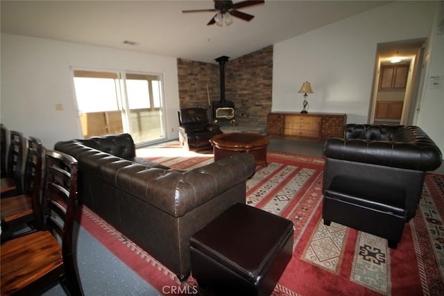 living area with visible vents, a wood stove, ceiling fan, and vaulted ceiling