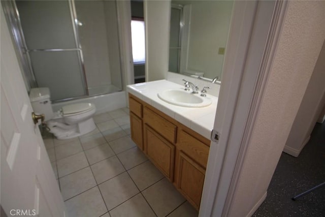 bathroom featuring shower / bath combination with glass door, toilet, vanity, and tile patterned flooring