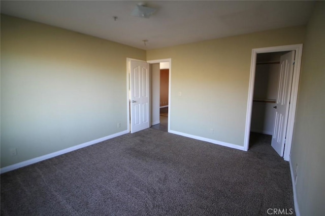 unfurnished bedroom featuring a closet, baseboards, and dark colored carpet