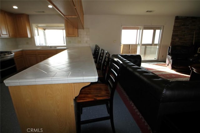 kitchen with backsplash, visible vents, tile countertops, and a peninsula