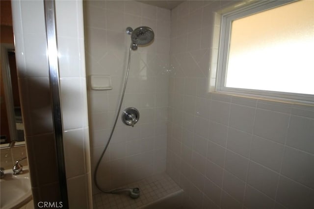 full bath with a sink and tiled shower