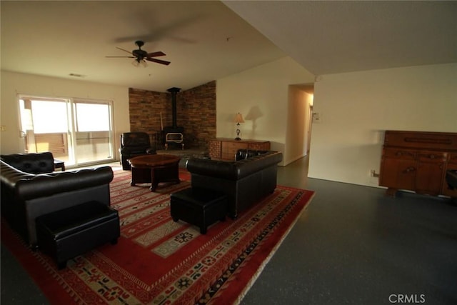 living area featuring lofted ceiling, a wood stove, and a ceiling fan