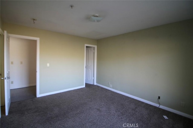 unfurnished bedroom with dark carpet and baseboards