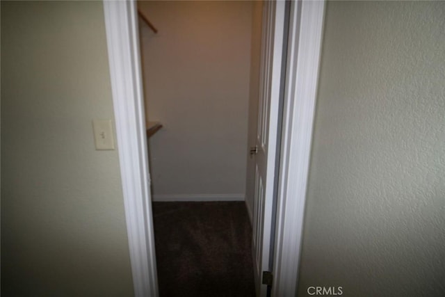 corridor with a textured wall, baseboards, and carpet floors