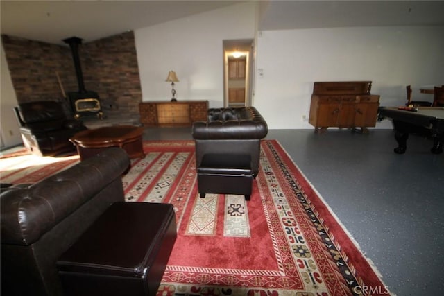 living room featuring speckled floor, a wood stove, and vaulted ceiling