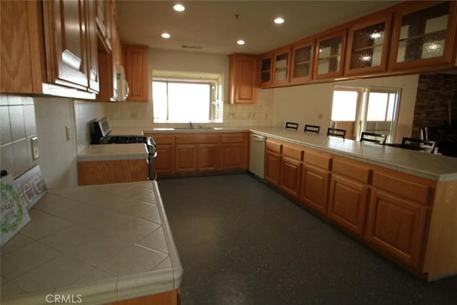 kitchen with white appliances, a peninsula, recessed lighting, glass insert cabinets, and tasteful backsplash