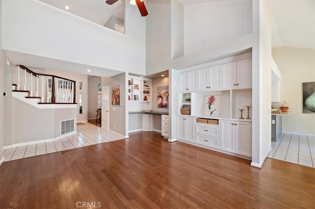 43966 Highlander Dr, Temecula, CA 92592 - unfurnished living room featuring hardwood / wood-style flooring, high vaulted ceiling, a ceiling fan, built in shelves, and stairway