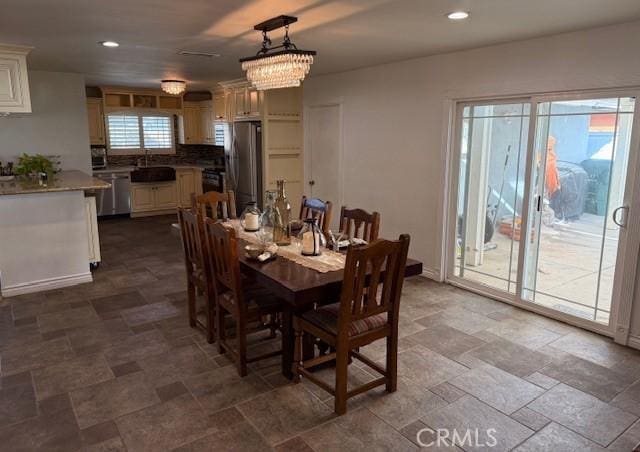 dining space with a chandelier, recessed lighting, stone finish floor, and baseboards