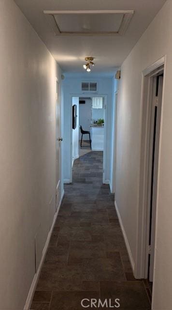 hallway featuring visible vents, baseboards, and attic access