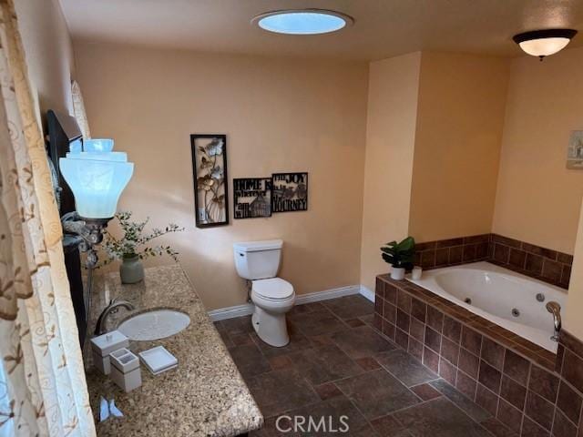 bathroom featuring toilet, stone finish flooring, a whirlpool tub, baseboards, and vanity