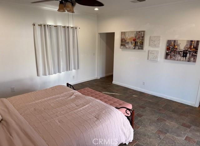 bedroom with visible vents, baseboards, ceiling fan, stone finish flooring, and crown molding