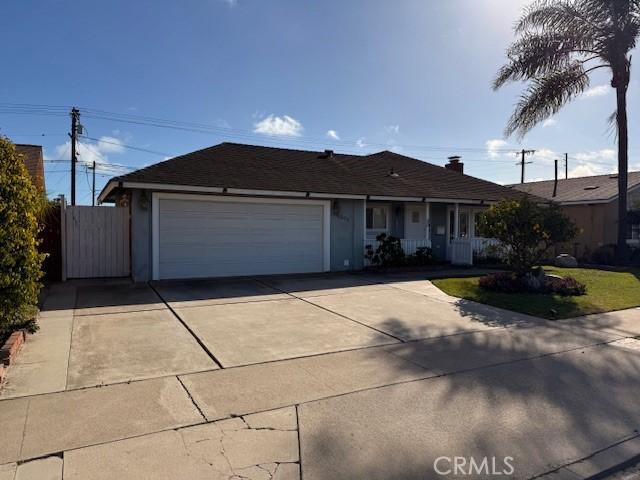 ranch-style house featuring an attached garage, a porch, driveway, and fence