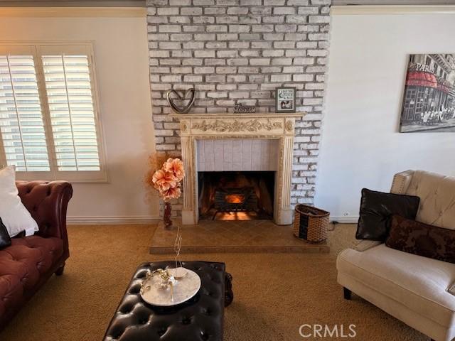 living area featuring a brick fireplace, carpet flooring, and baseboards