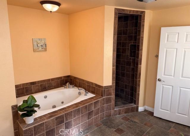 bathroom featuring a tile shower and a tub with jets