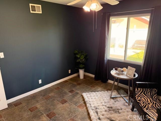 interior space with visible vents, baseboards, ceiling fan, and stone finish flooring