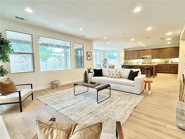 living area with recessed lighting, visible vents, baseboards, and light wood finished floors