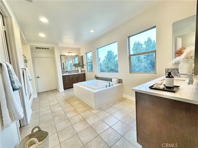 full bathroom featuring visible vents, two vanities, tile patterned flooring, baseboards, and a bath