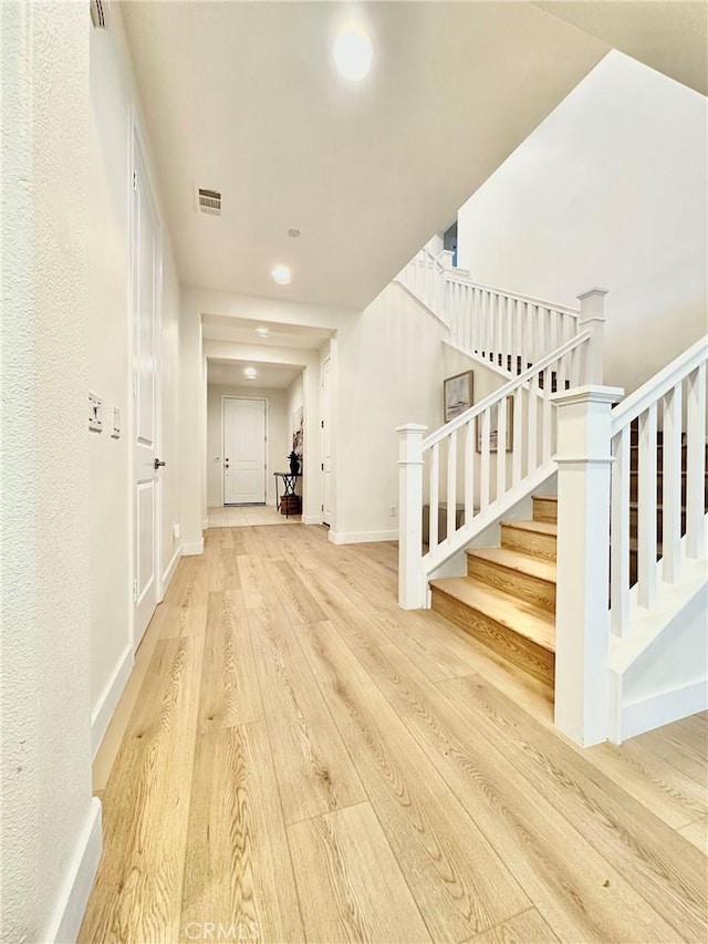 interior space with visible vents, baseboards, wood finished floors, and stairs